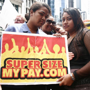 Two protesters holding a super size my pay dot com sign