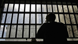 Man standing in a prison behind bars